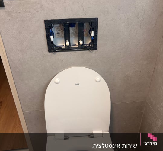 אסלה עם מכסה פתוח ותיקון בקיר מאחוריה